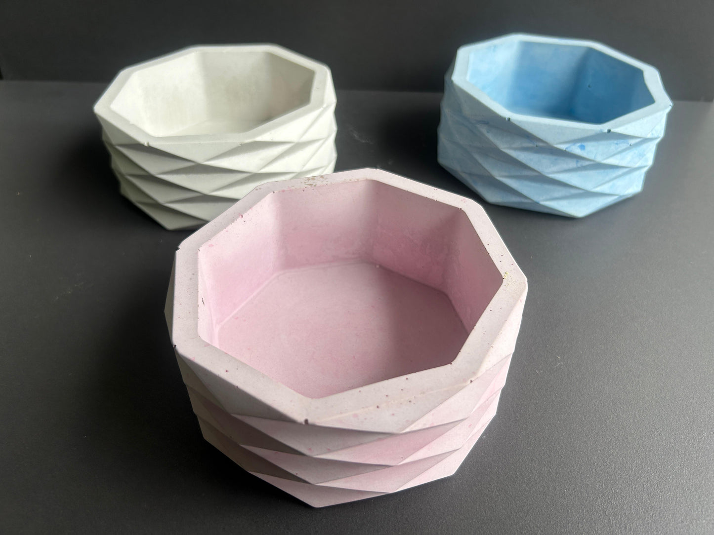 Three geometrically shaped bowls in white, pink, and blue