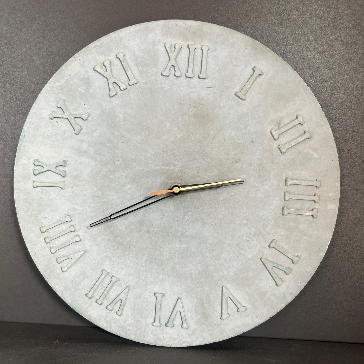 Concrete wall clock with Roman numerals on a gray background