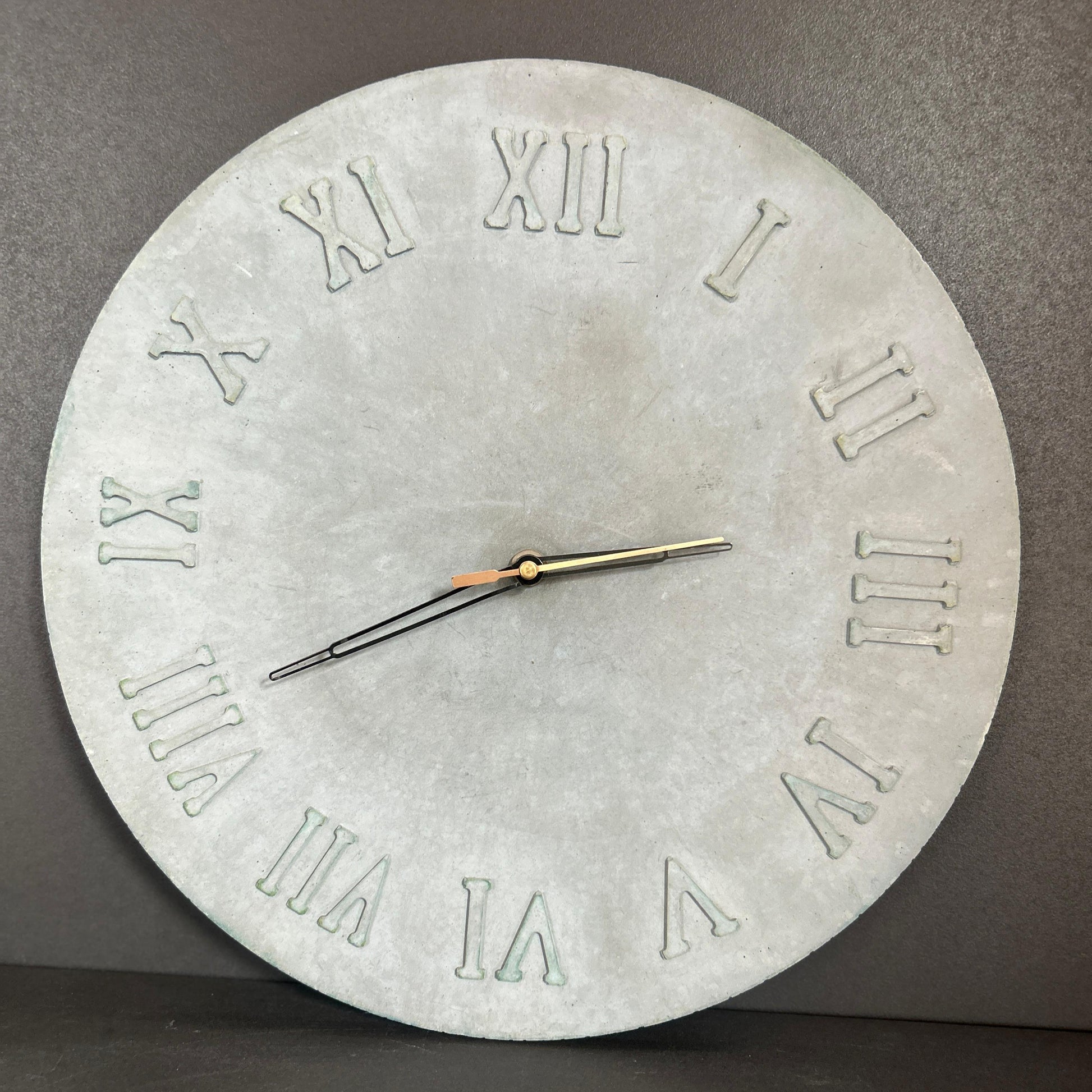 Concrete wall clock with Roman numerals on a gray background