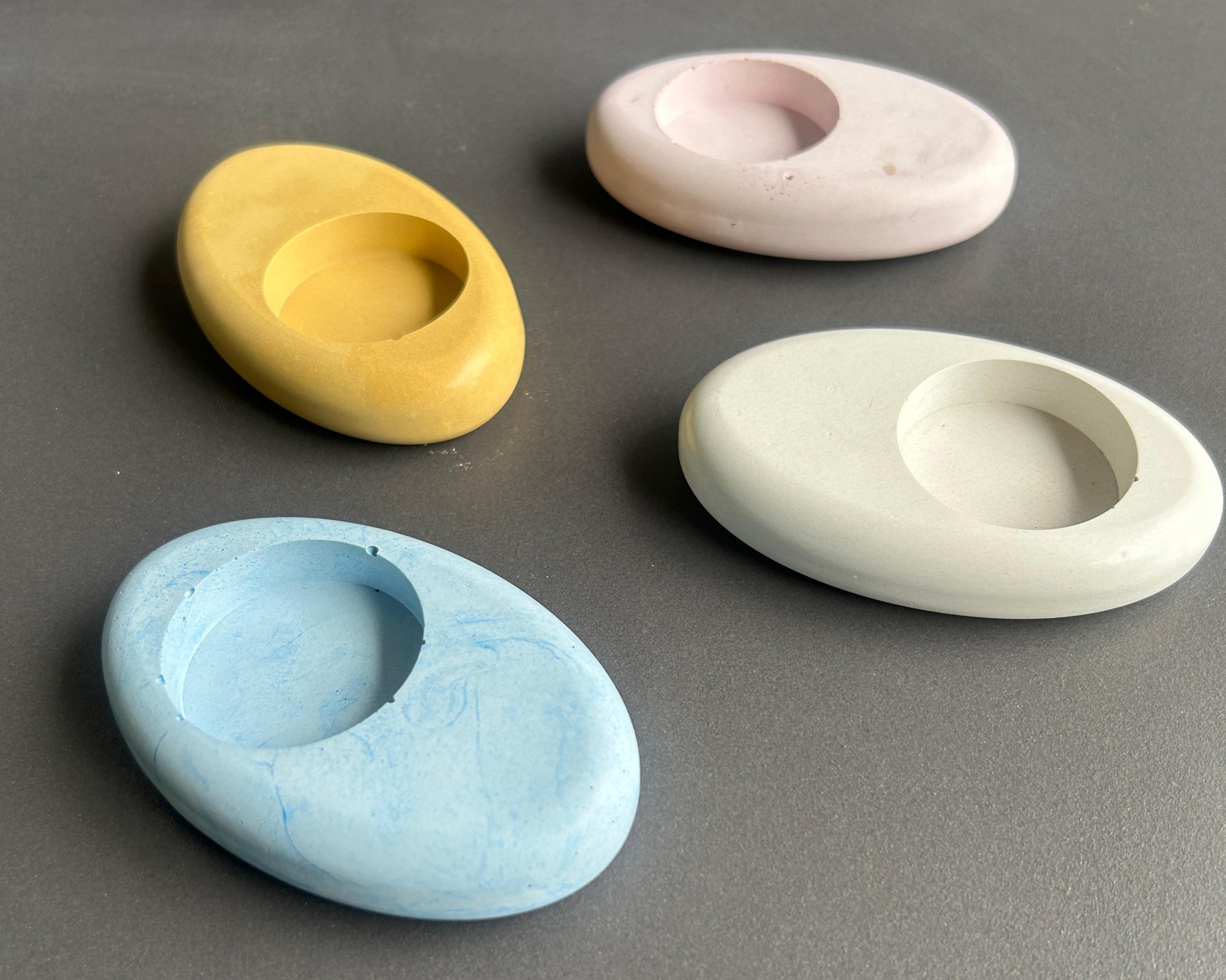 Four concrete candle holders in pastel colors 