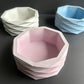 Three geometrically shaped bowls in white, pink, and blue 